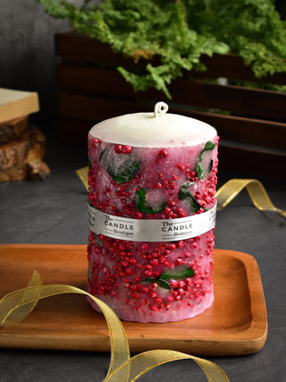 Pillar candle with red dry flowers and green leaves