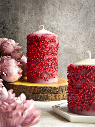 "Pillar candle with red dried flowers"